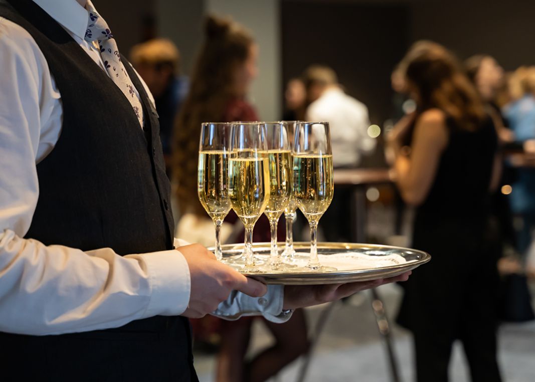Bediende met een blad met champagneglazen in een feestzaal bij Restaurant 't Edelhert, perfect voor bruiloften, verjaardagen en jubileums.